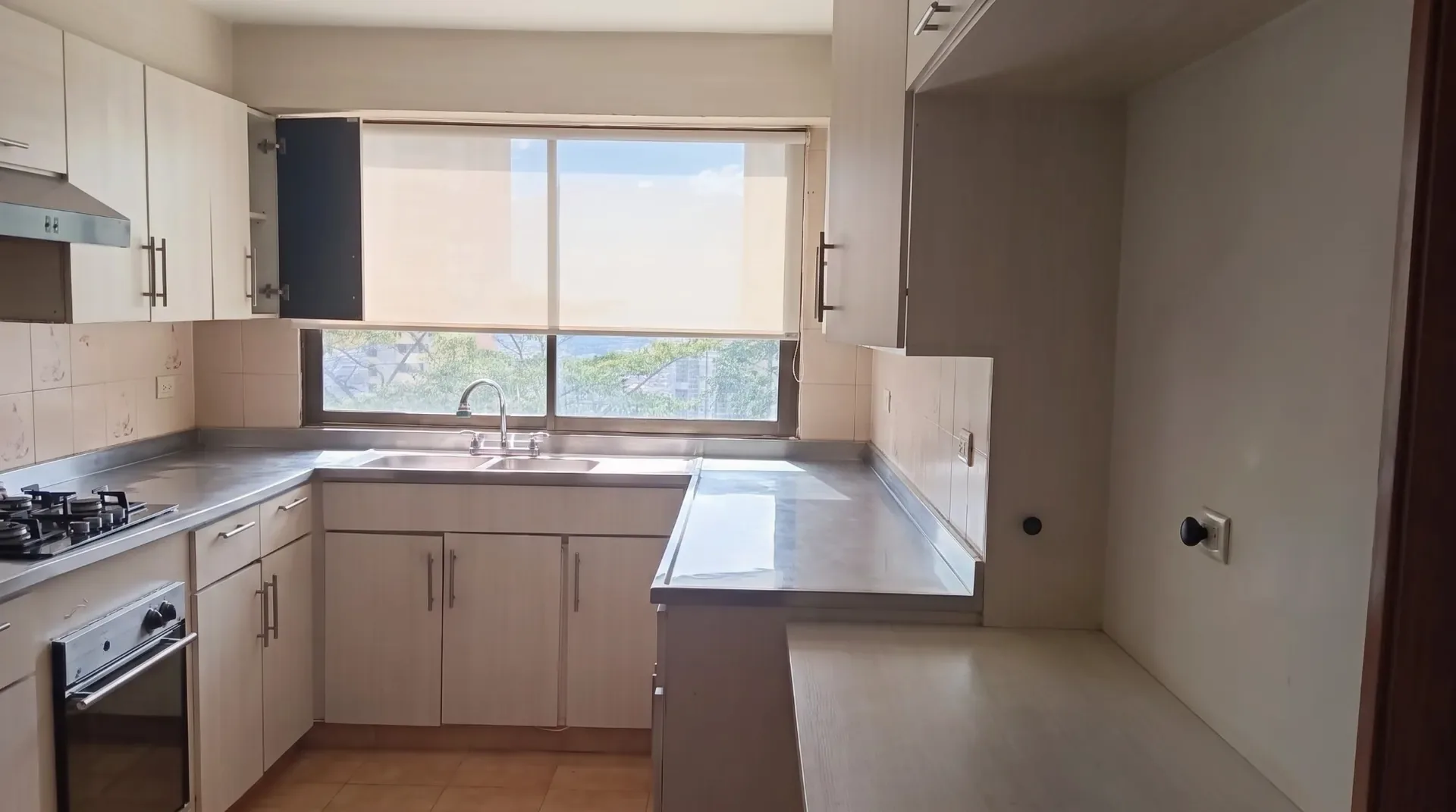 Cocina en U con barra y una ventana con persiana.