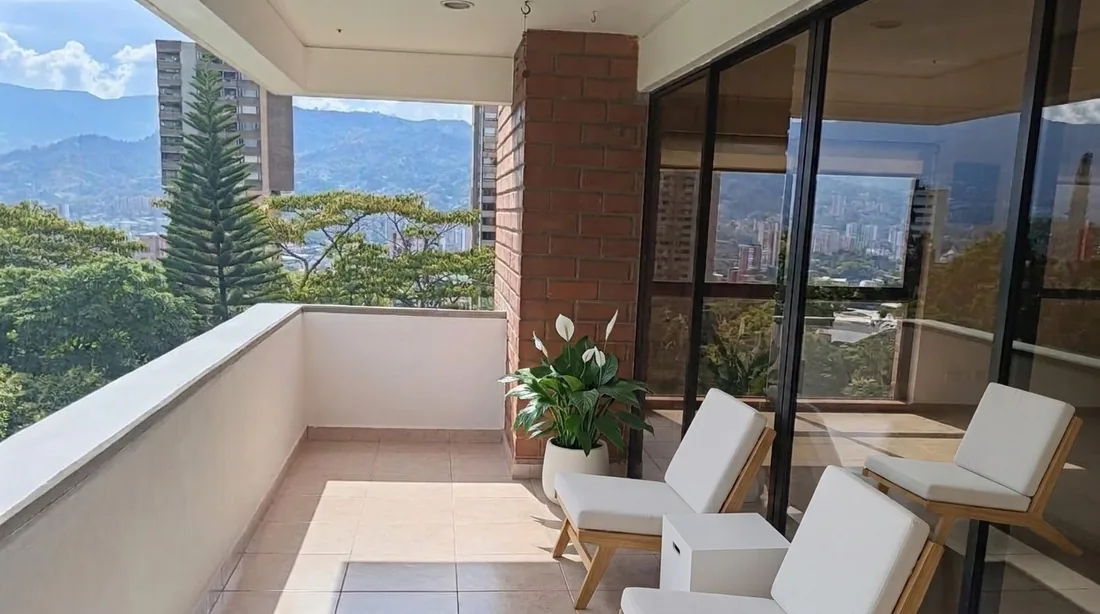 Terraza cubierta con vista a la montaña, con amoblamiento virtual: tres sillones de exterior, una mesa auxiliar y una planta.